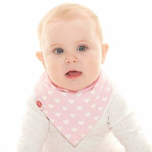 Baby wearing a pink bib with white heart patterns on a white background