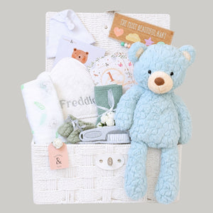 Baby gifts hamper basket with presents including blue teddy bear and personalised baby towel 