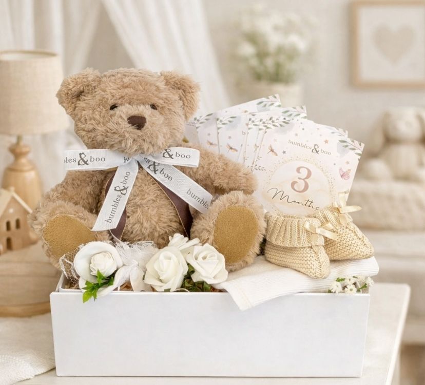 A hamper for a new baby with a teddy bear and milestone cards in a gifts box