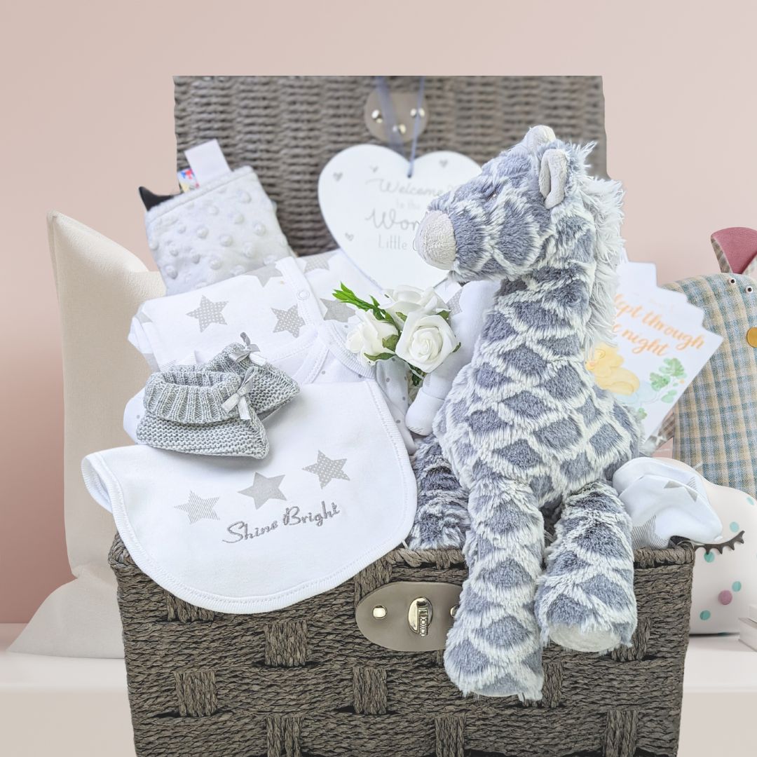 baby hamper basket with giraffe theme. Includes large soft giraffe, baby clothing set in white, sensory taggie blanket, milestone cards, booties and nursery plaque.