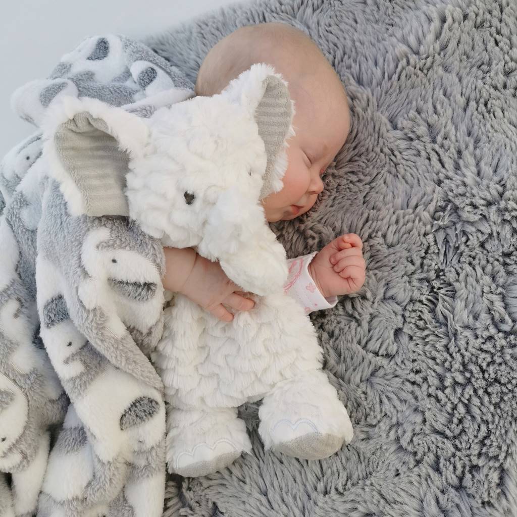 baby cuddling white elephant toy