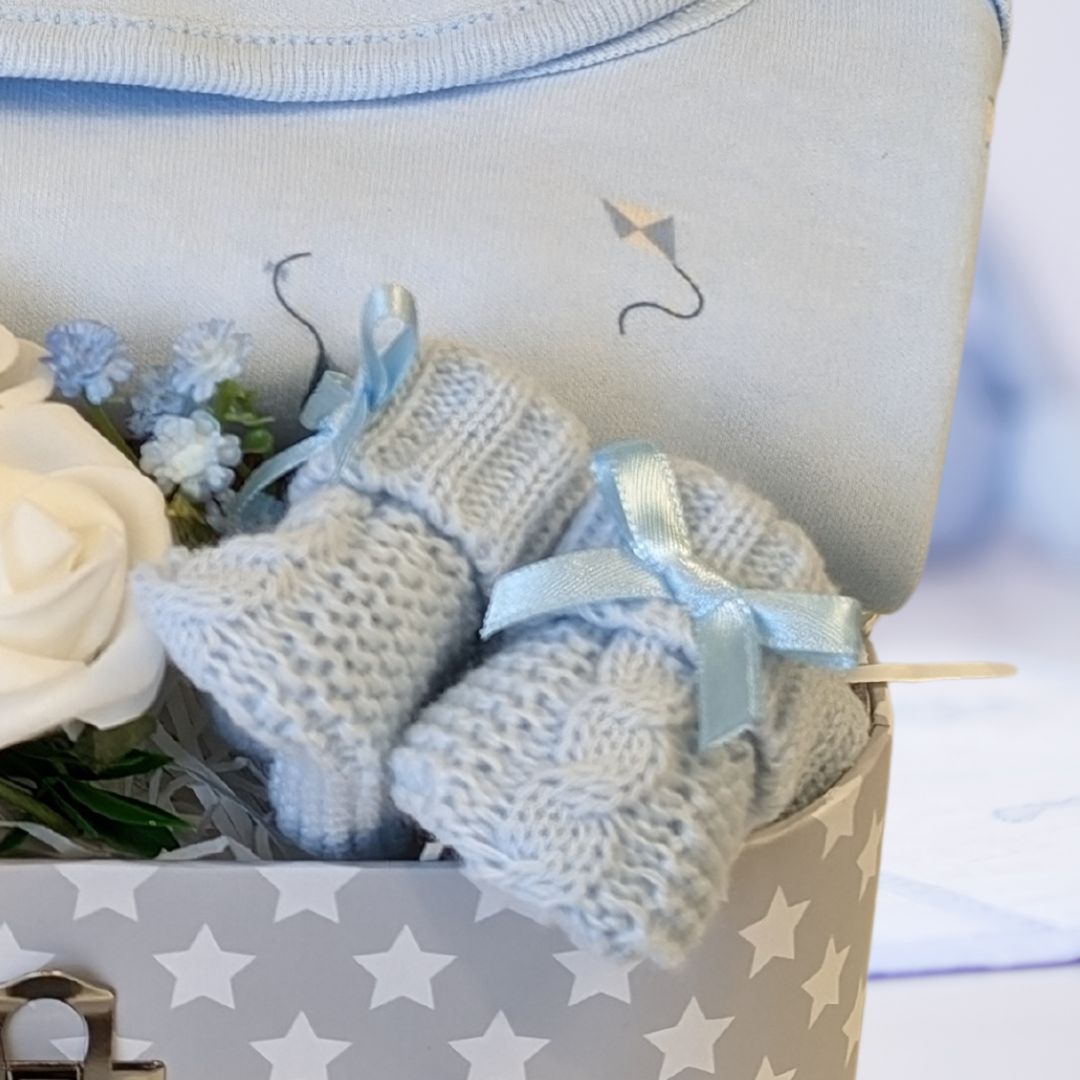 baby boy gifts trunk with blue clothing set and blue knit booties