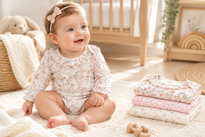 Baby sitting in a long sleeve floral bodysuit from the three pack.
