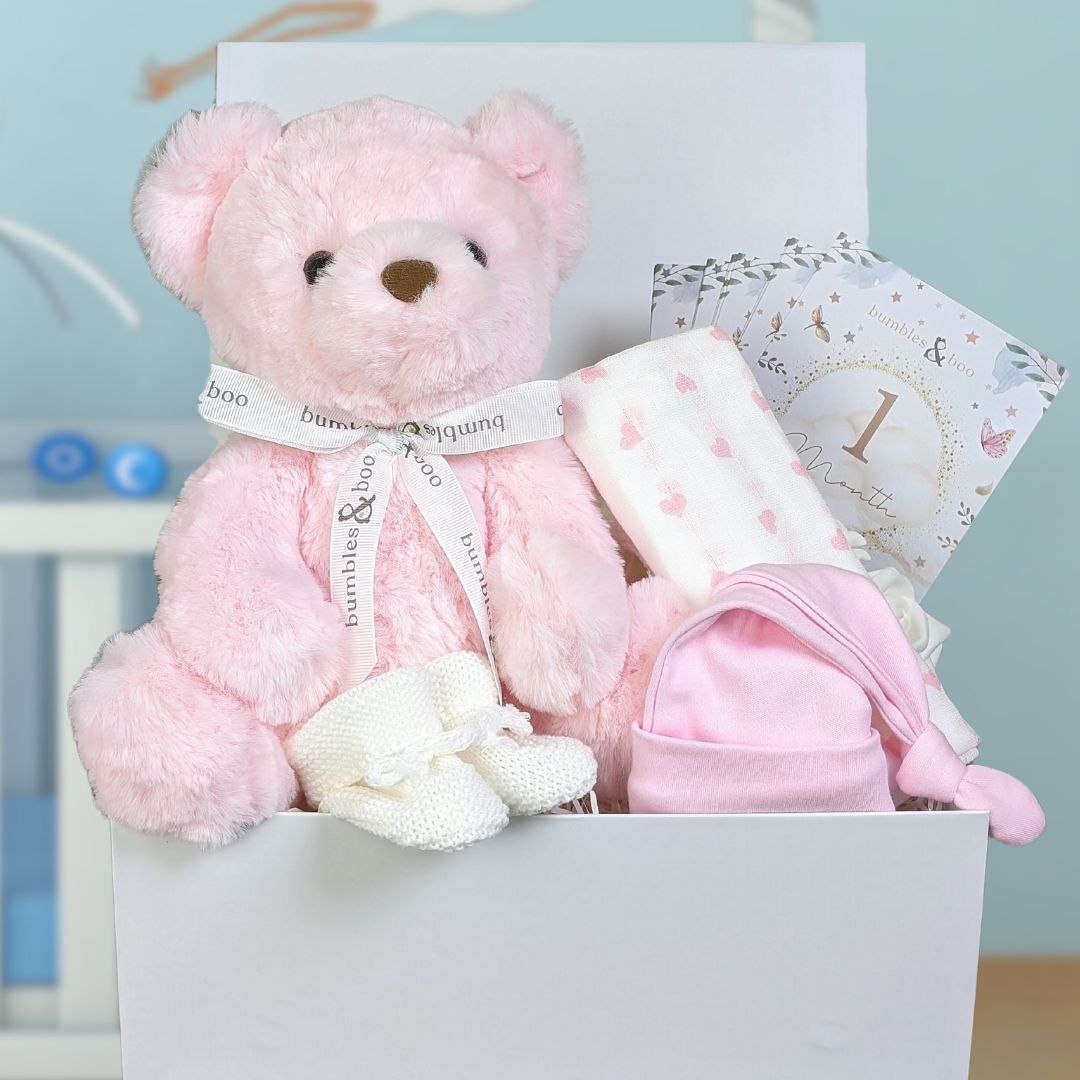 Baby girl gift box with teddy bear and many practical items for the new parents.