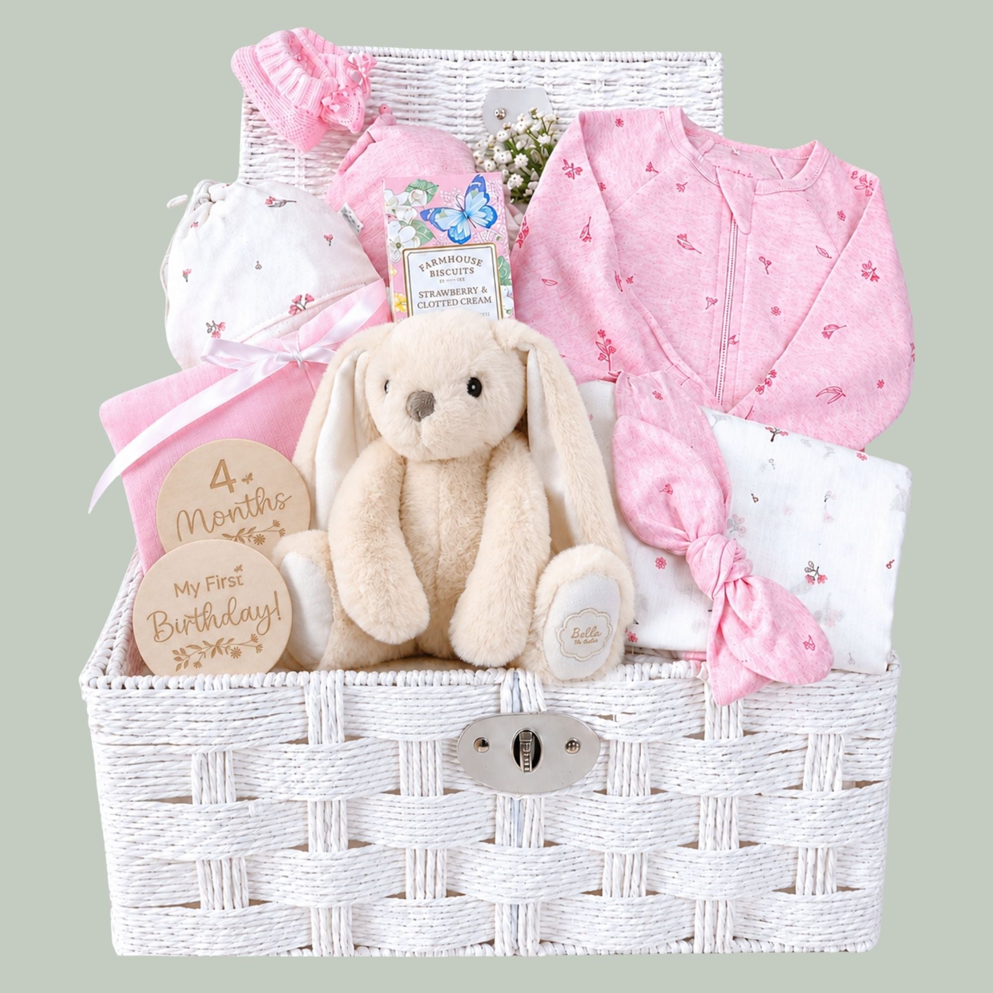 Newborn baby girl gifts in a white hamper basket with organic pink baby clothing and bunny soft toy.