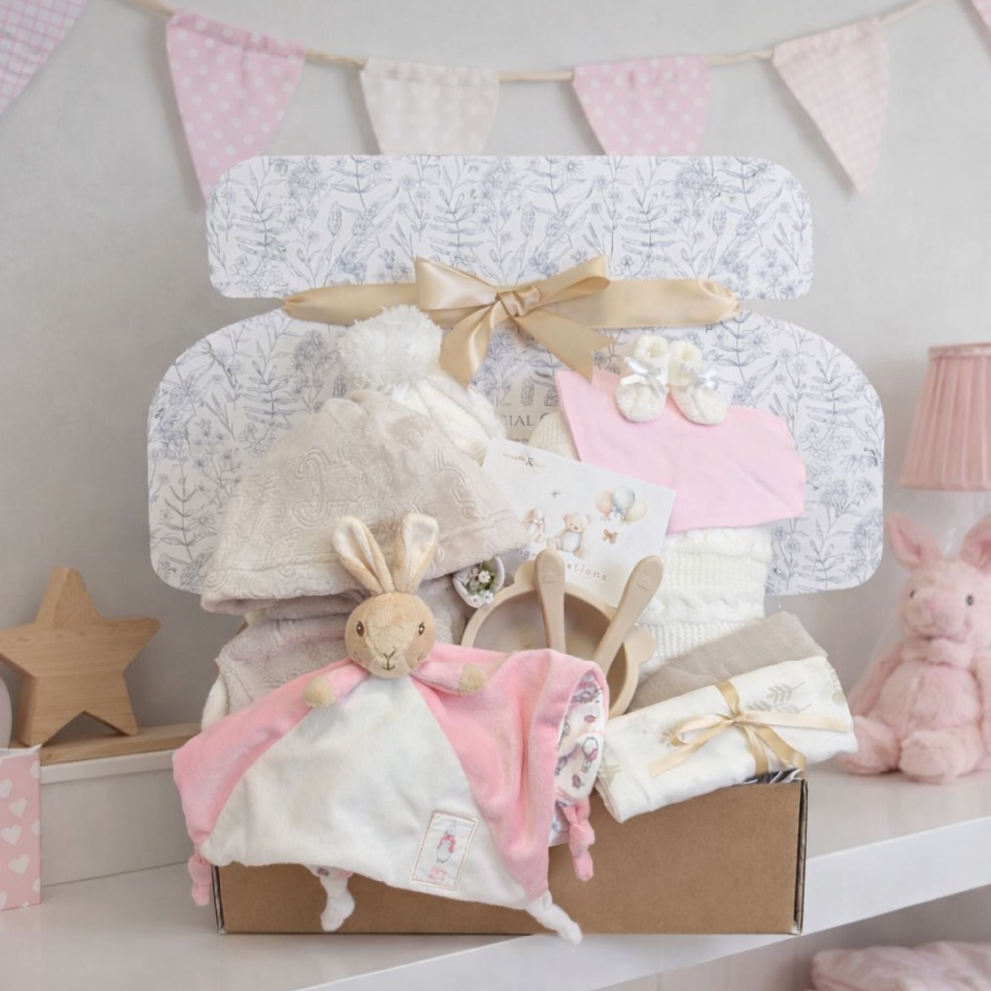 New baby girl hamper presented in an eco-friendly gift box. With pink and cream gifts including flopsy bunny, blanket and dressing gown.