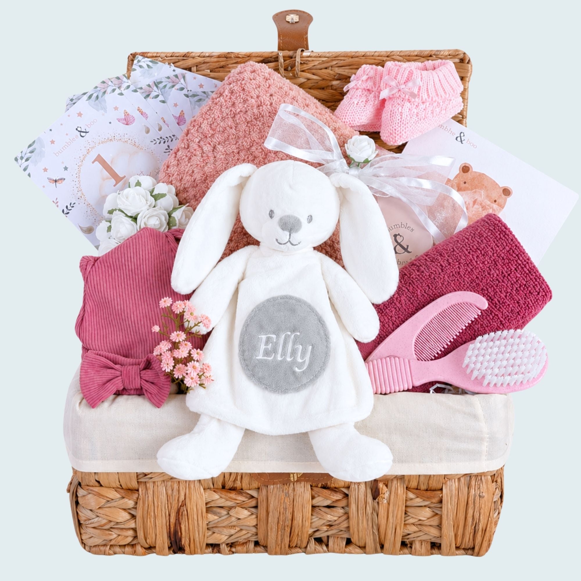New baby girl hamper basket with gifts including white bunny toy and dark pink baby essential presents from Bumbles & Boo.