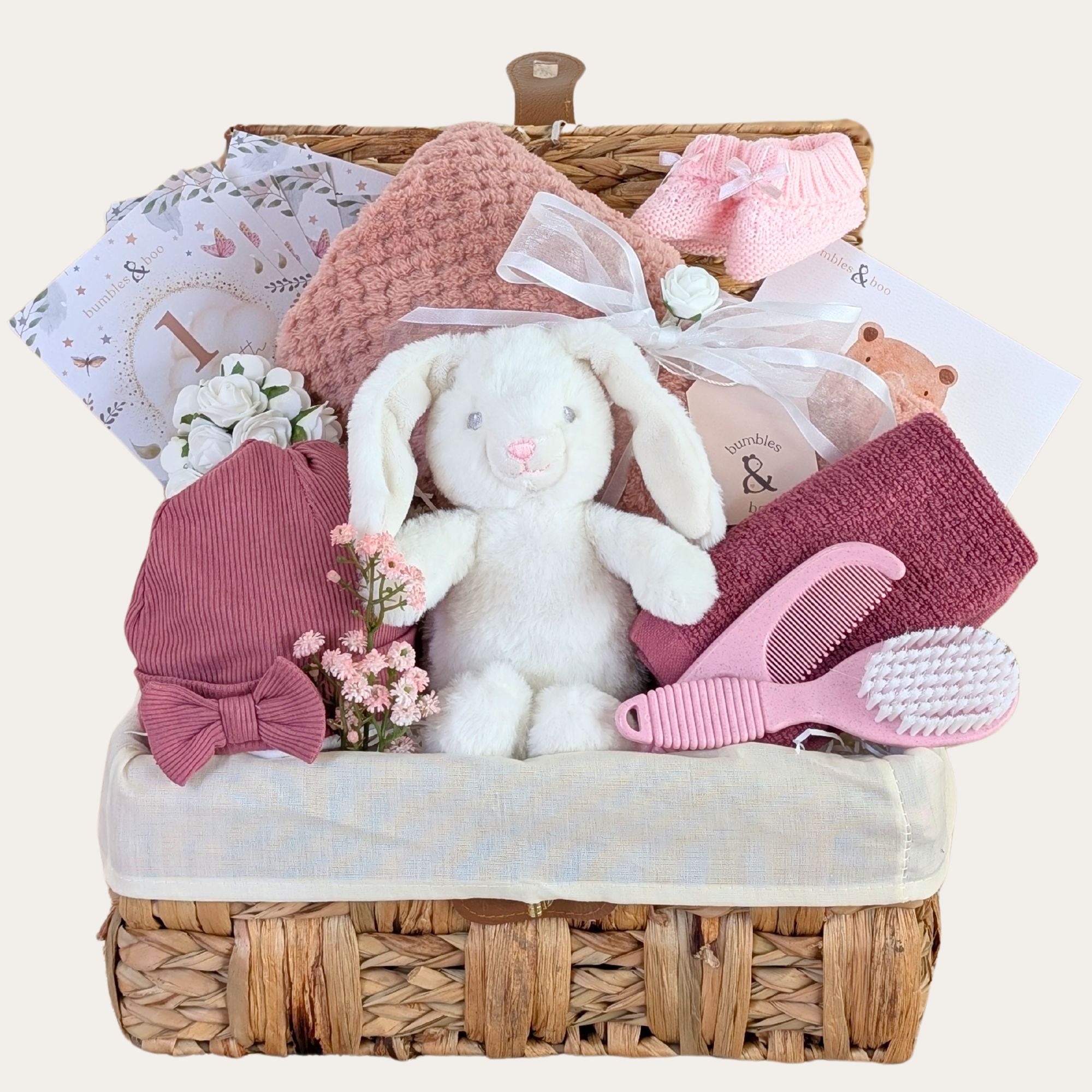 New baby girl hamper basket with gifts including white bunny toy and dark pink baby essential presents from Bumbles & Boo.