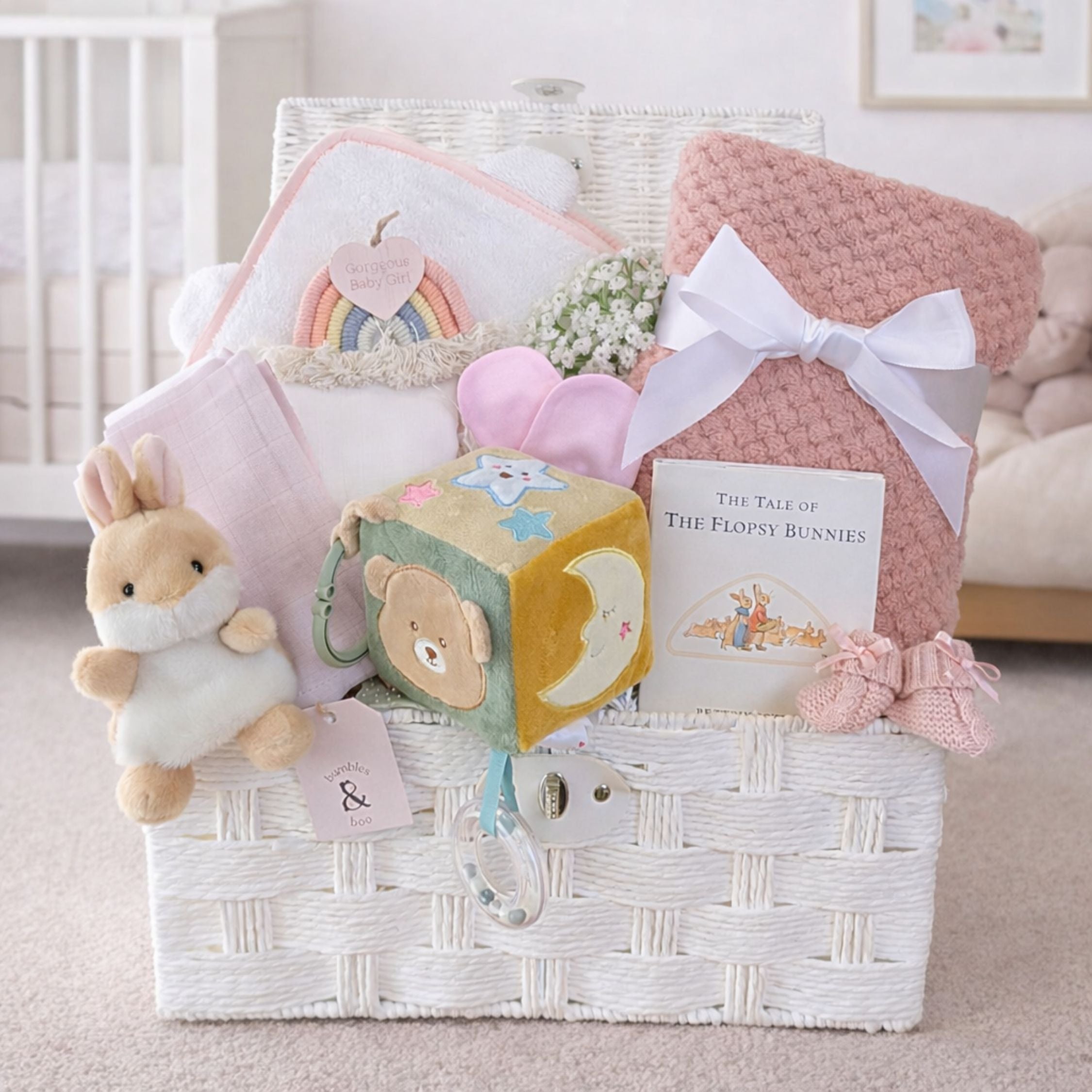 Baby girl gifts hamper with congratulations presents with a bear and bunny theme in a white gift basket.
