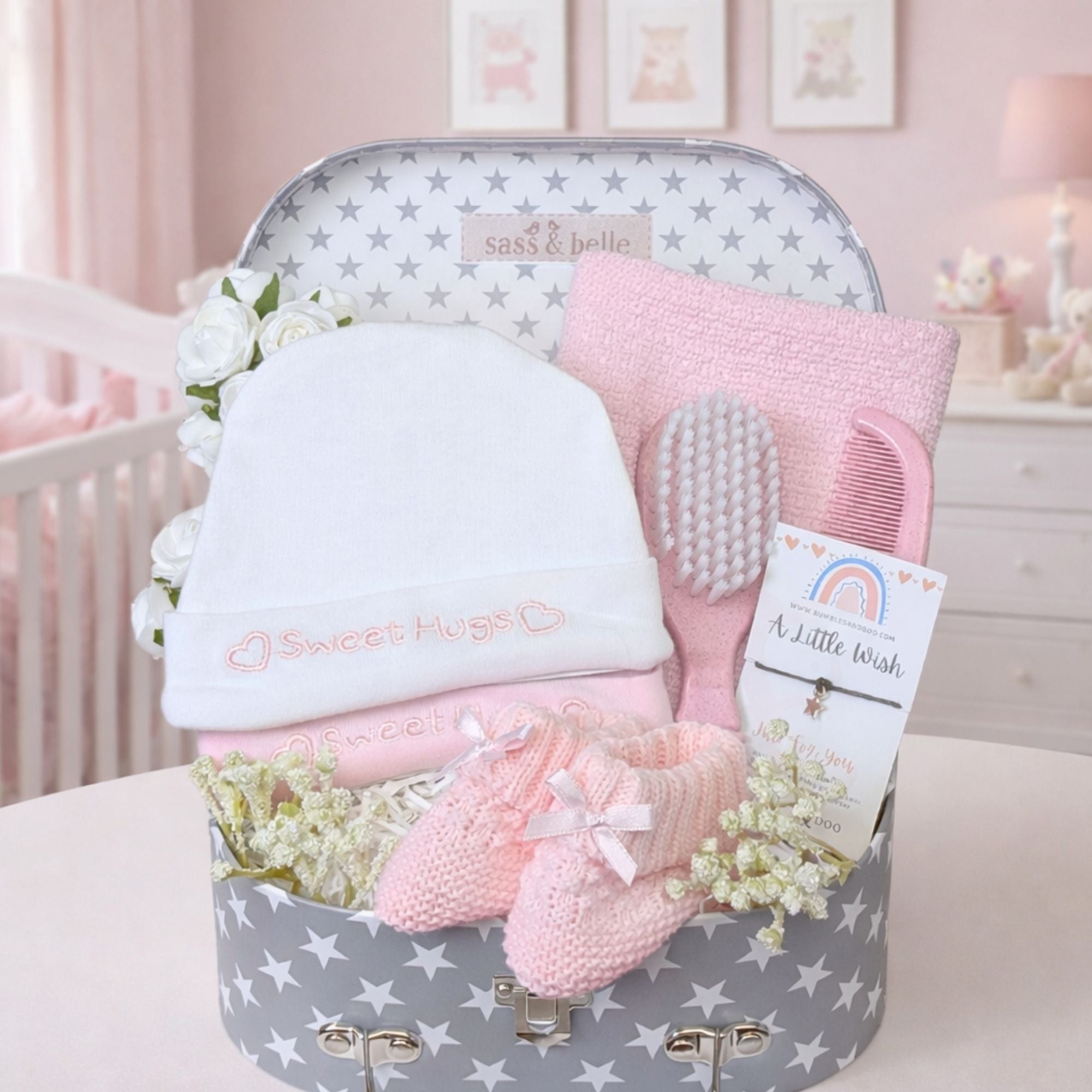Baby girl hamper with gifts including hats which read sweet hugs in embroidery and pink accessories