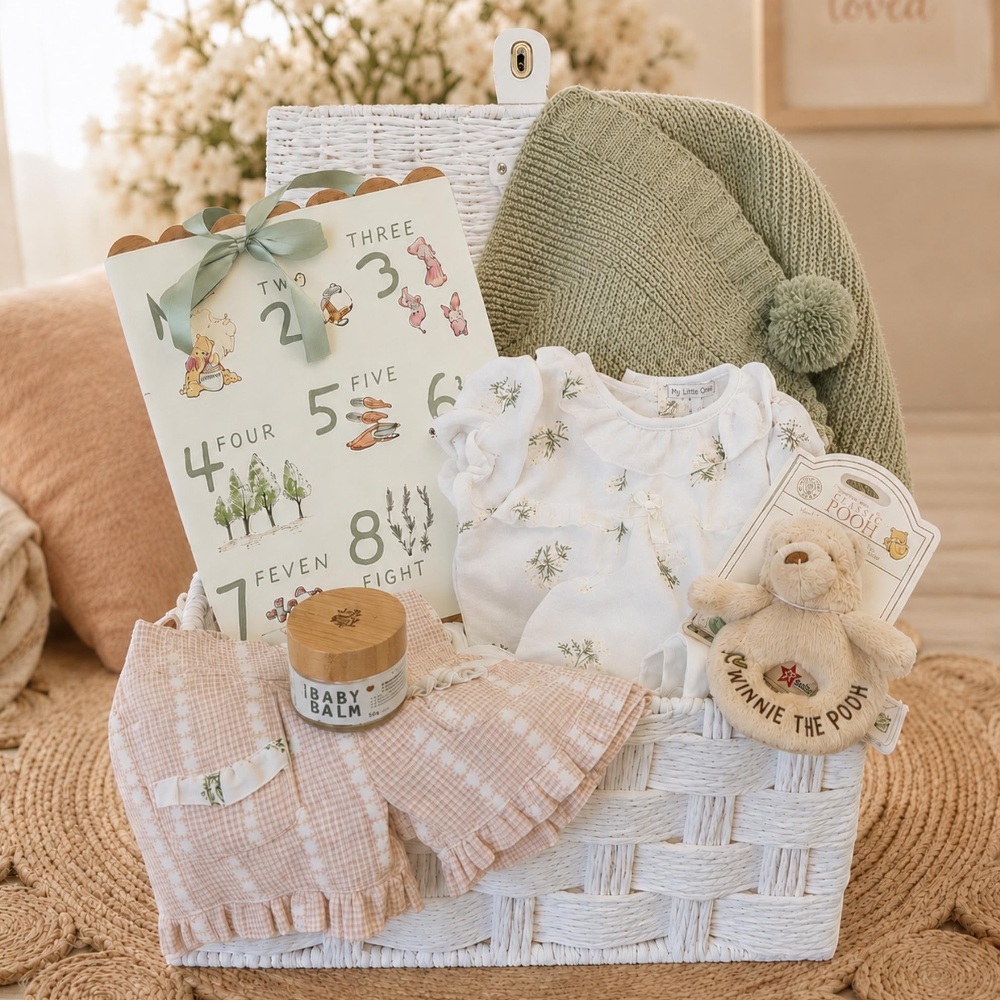 Baby girl gifts basket with items including baby blanket, clothing set and winnie the pooh rattle