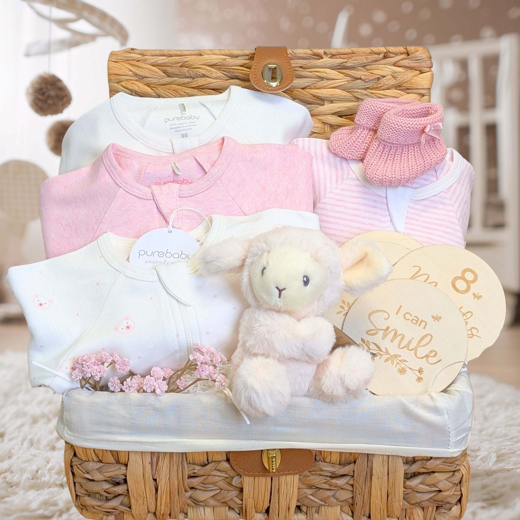 Baby girl hamper basket with pink & white baby clothes set and gifts including milestone discs and lamb soft toy.