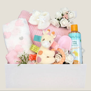 Newborn baby girl hamper. This white gifts box contains presents including a pink cellular blanket, muslin square and tilly giraffe teether. Bumbles and Boo.