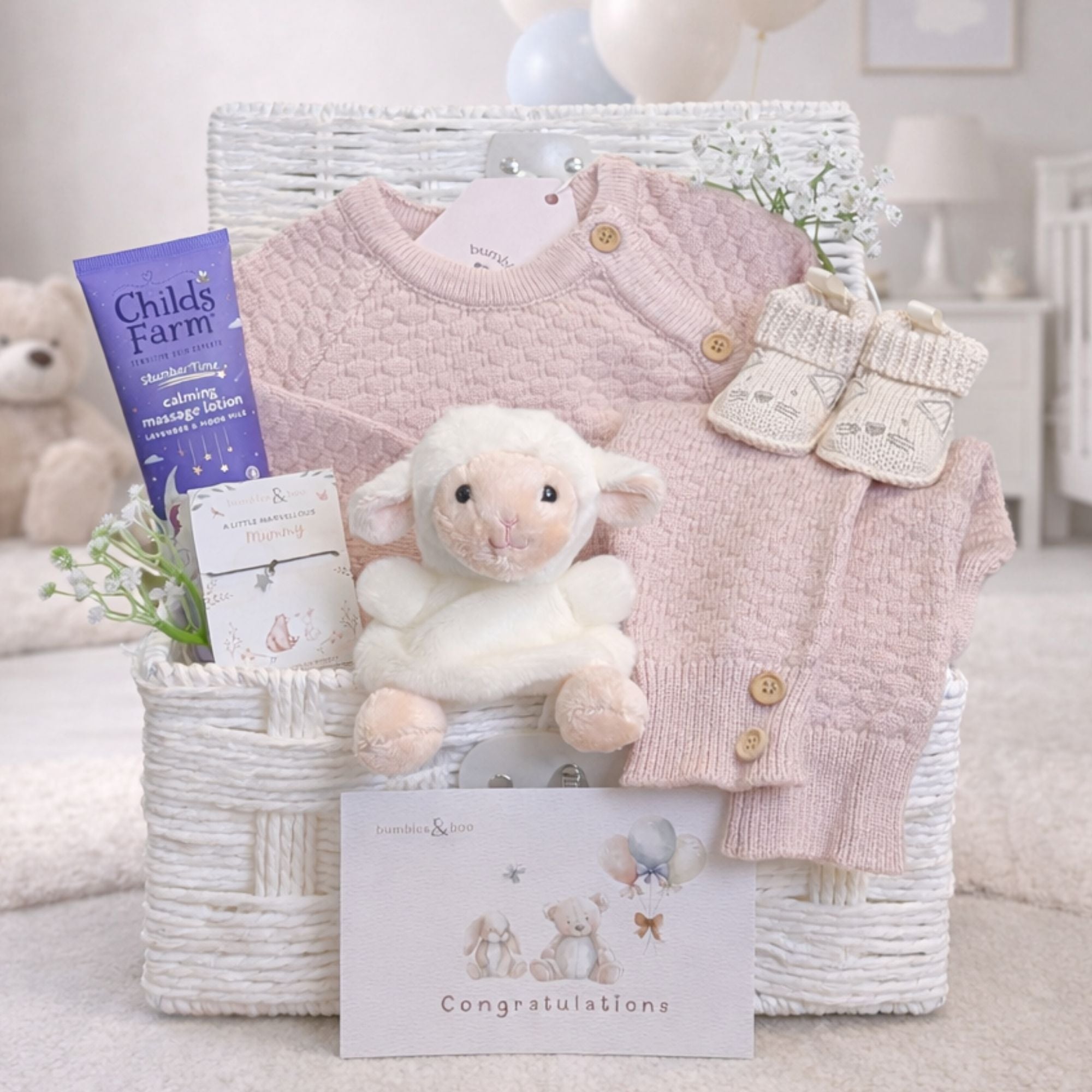Luxury baby girl gifts in a hamper basket with dusty pink knit clothing set and a lamb toy.