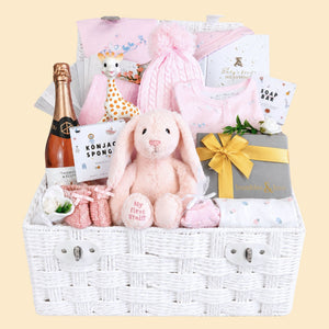 Baby girl gifts in a hamper basket with pink and white presents including pink Steiff bunny and treats for parents.