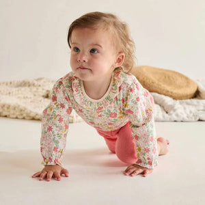 Baby crawling in the colourful long sleeve floral bodysuit.