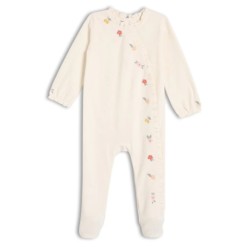 Baby girl wearing cream velour embroidered sleepsuit with matching comforter toy