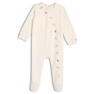 Baby girl wearing cream velour embroidered sleepsuit with matching comforter toy