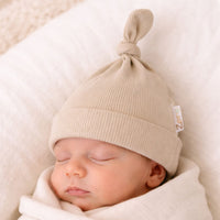 Beige ribbed baby hat with a little knot