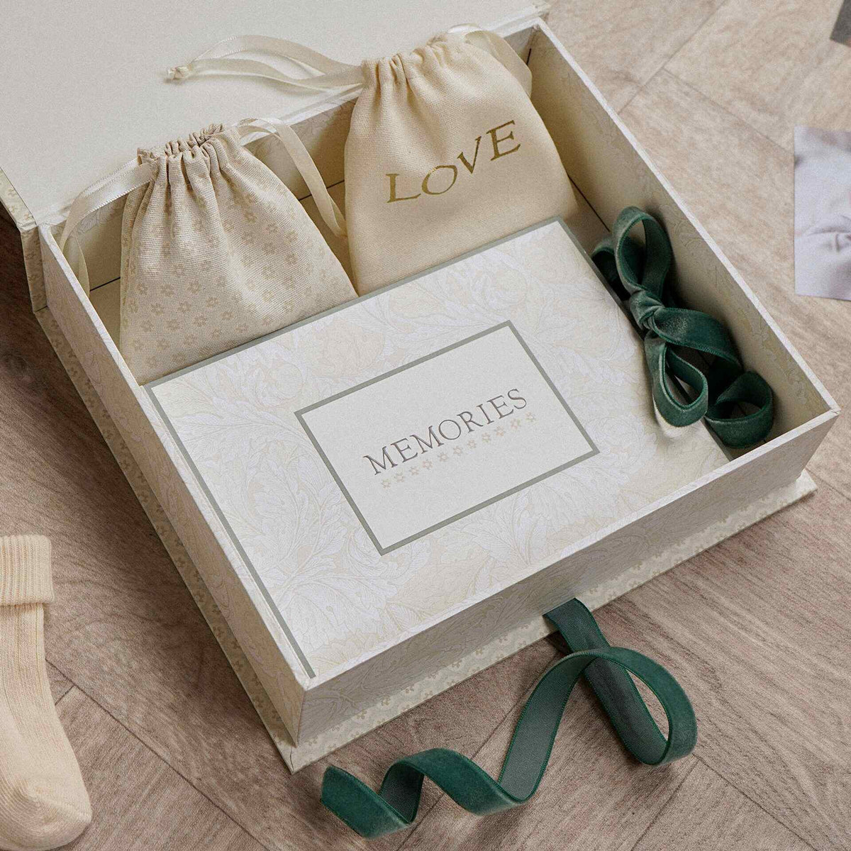 Overhead view inside the baby keepsake box showing two pouches and green ribbon details.