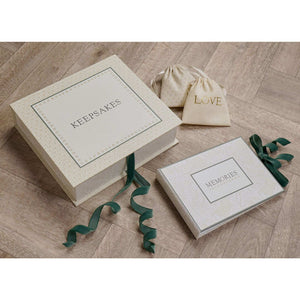 Baby keepsake box styled with a ‘LOVE’ pouch and matching ‘MEMORIES’ item on a wooden surface.