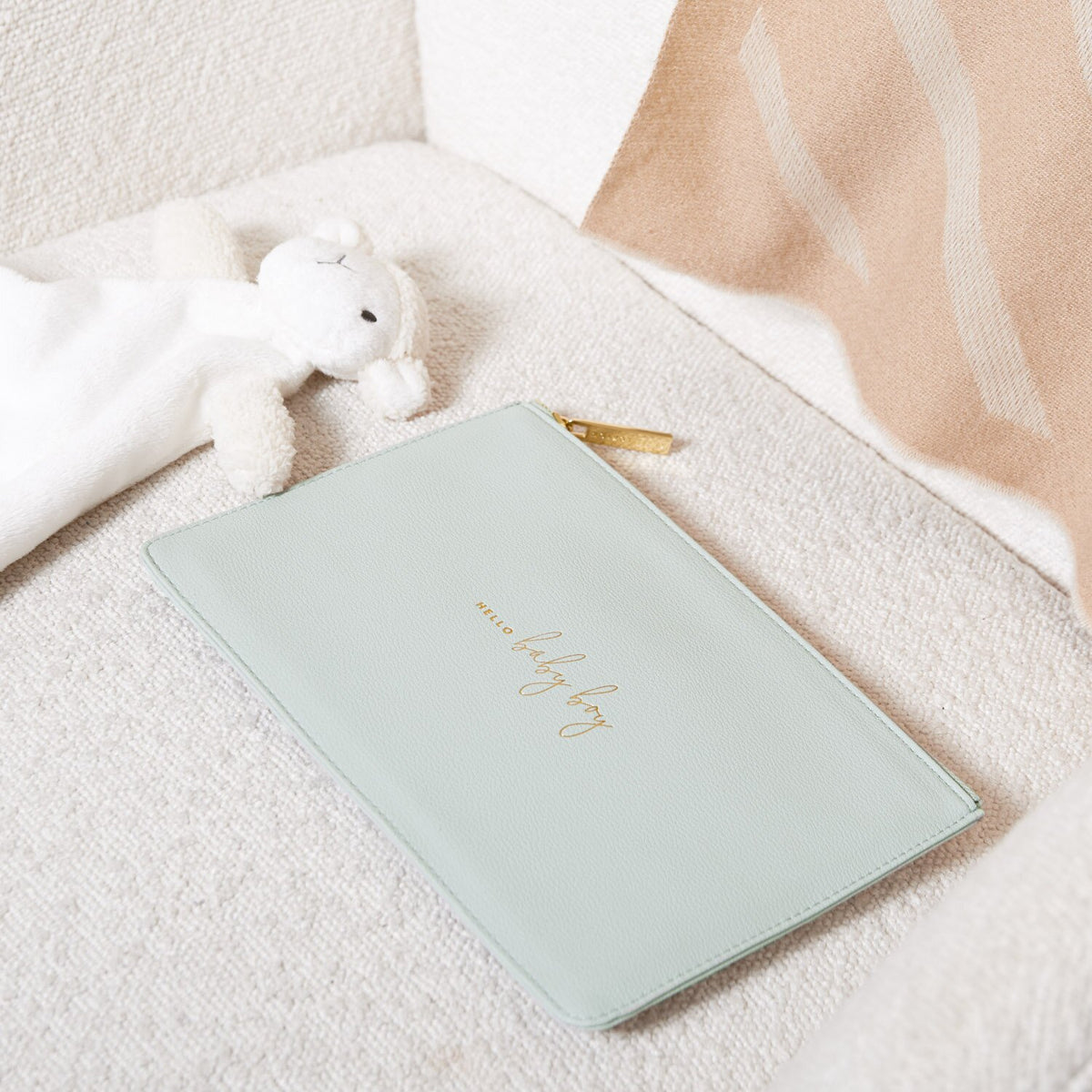Cool-grey Hello Baby Boy pouch with gold-tone lettering and zip, styled beside a white soft toy.