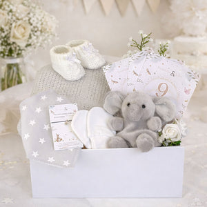 A baby box full of baby shower presents including an elephant and blanket.
