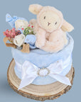 Blue nappy cake baby shower gifts, topped with lamb soft toy.
