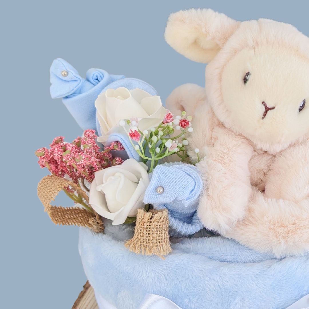 Stunning baby boy nappy cake brimming with all things baby. Perfect gift for a baby shower or to welcome a new baby into the world. Contains blanket, nappies, teddy bear, muslins, socks and mittens.