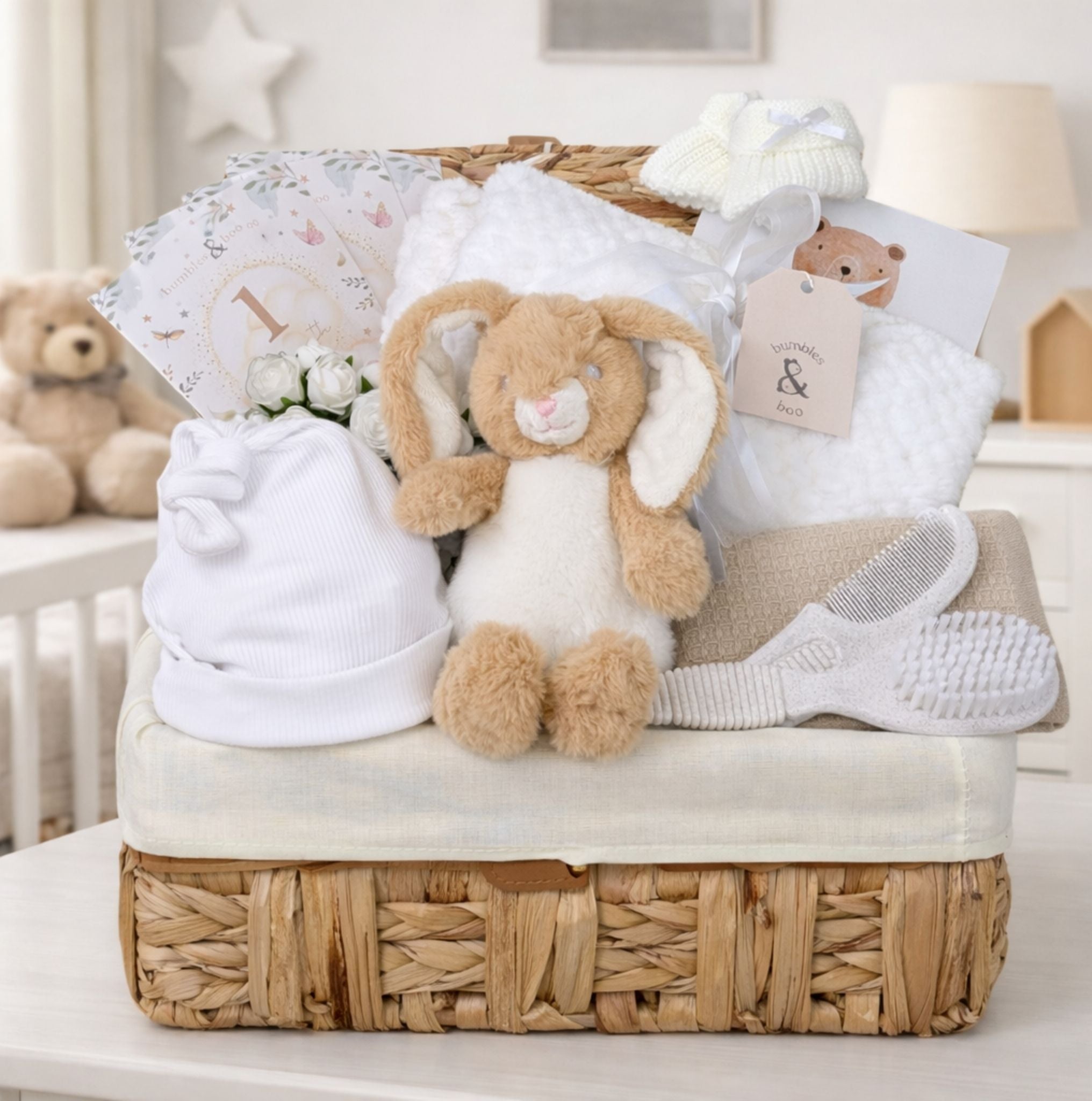 Baby shower gifts basket with white and cream presents packed in a wicker hamper with bunny toy