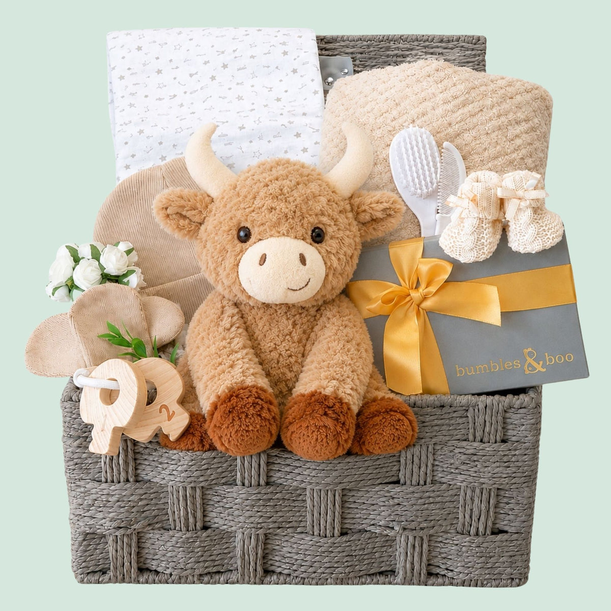 Baby shower gifts hamper with presents including plush highland cow and chocolates for the mum to be
