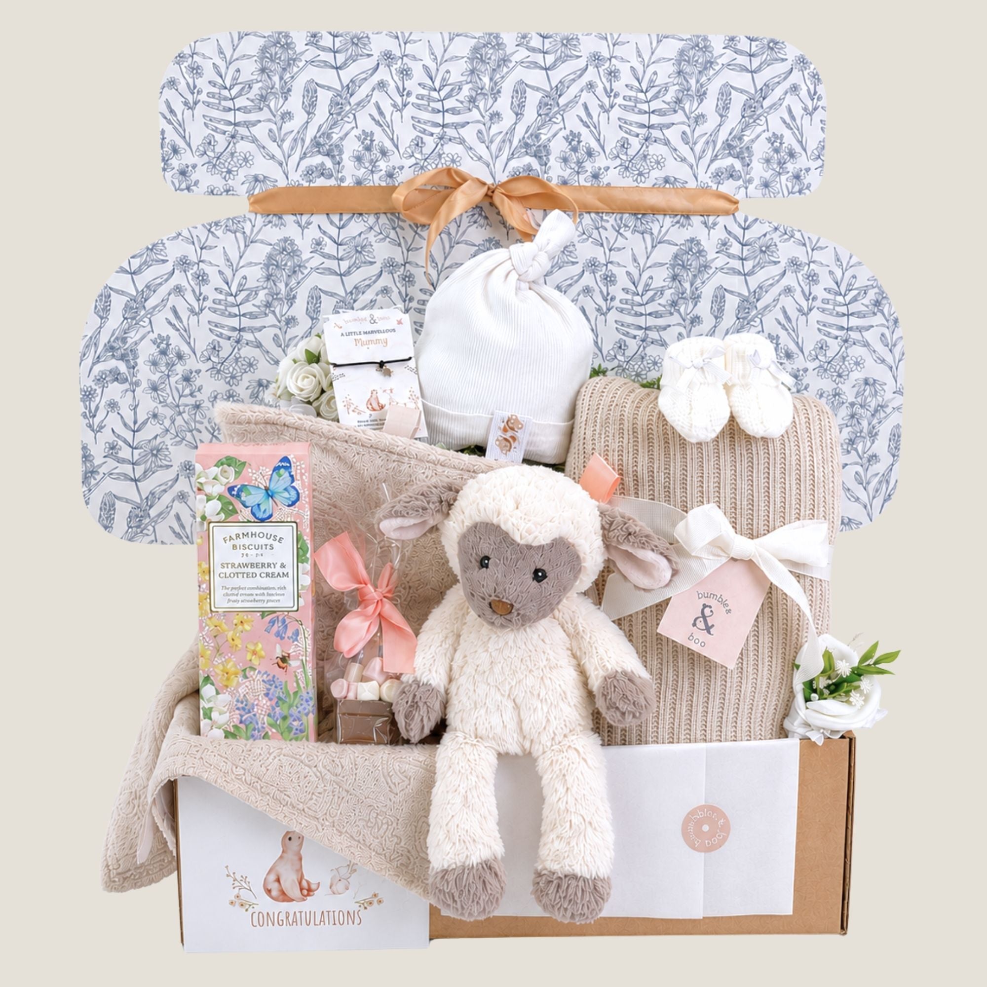 Luxury baby shower gift box beautifully wrapped in tissue and ribbon, filled with neutral baby essentials and gifts for mum.