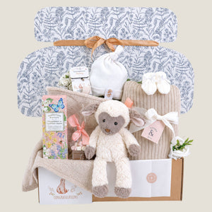 Luxury baby shower gift box beautifully wrapped in tissue and ribbon, filled with neutral baby essentials and gifts for mum.