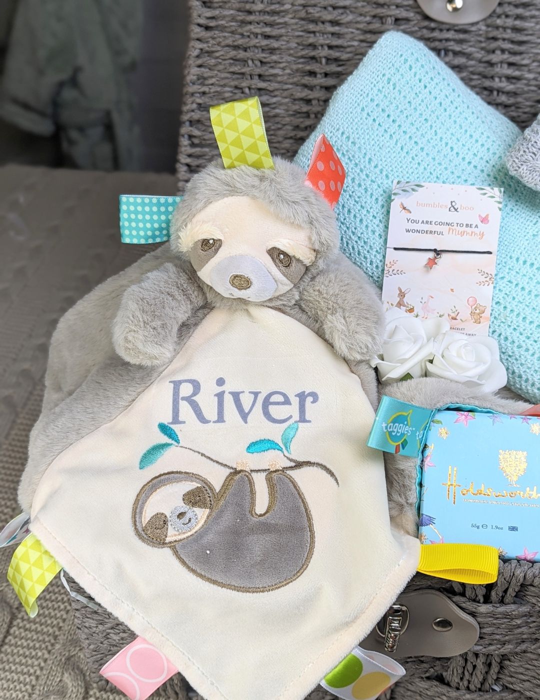 baby boy gifts basket with sloth blankie, mint green blanket, baby wash and treat for the parents.