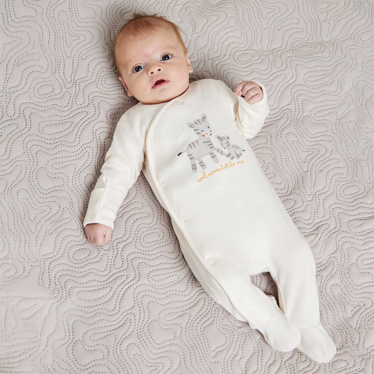 Baby wearing unisex cream zebra embroidered sleepsuit with enclosed feet