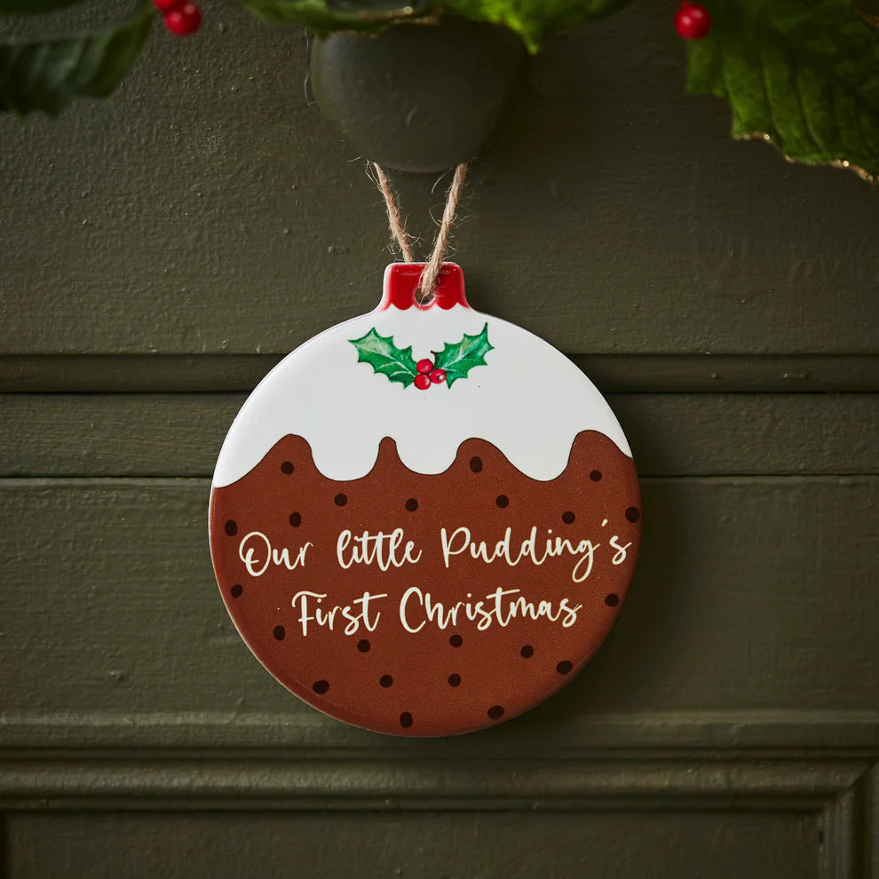 A ceramic Christmas decoration in the shape of a Christmas pudding with the wording 'Our Littles Pudding's First Christmas