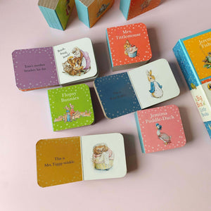 Beatrix Potter mini story books arranged on pink background