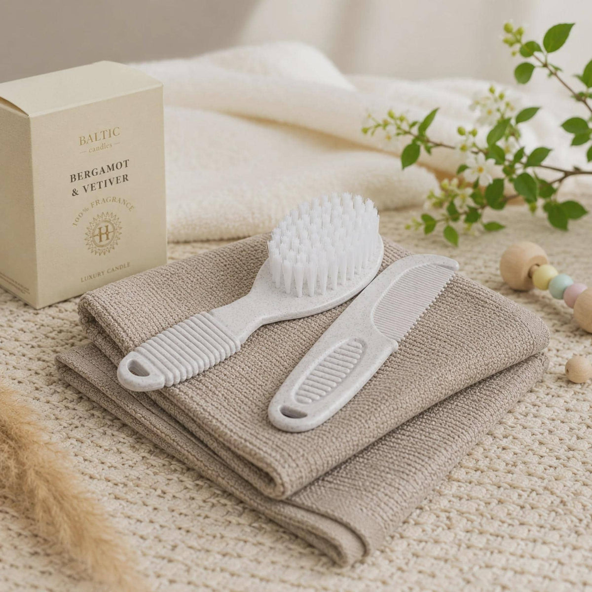 White baby brush and comb placed on folded neutral cloths.