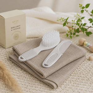 White baby brush and comb placed on folded neutral cloths.