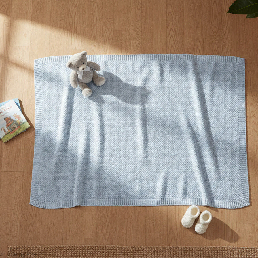 Blue bamboo baby blanket with soft knitted weave laid flat and styled in a neutral nursery
