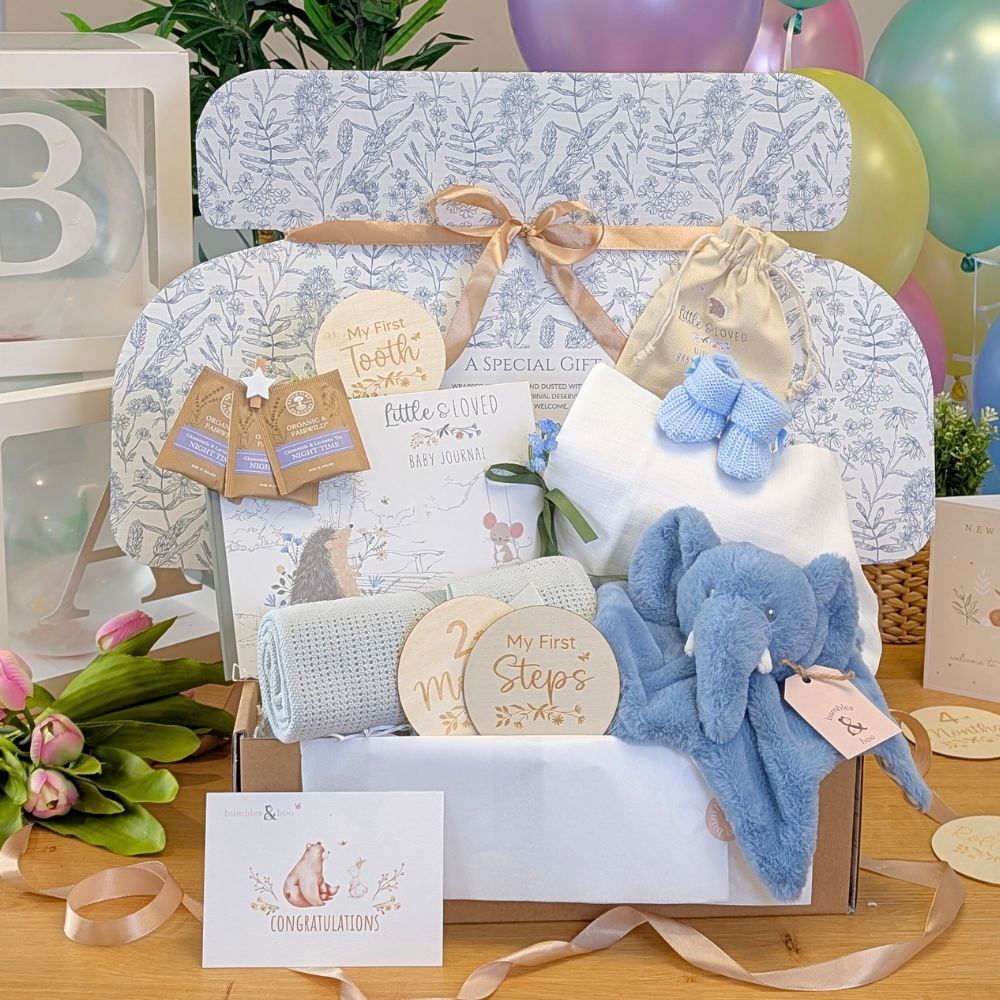 Baby gifts box with blue elephant toy, blanket, and other baby boy gifts.
