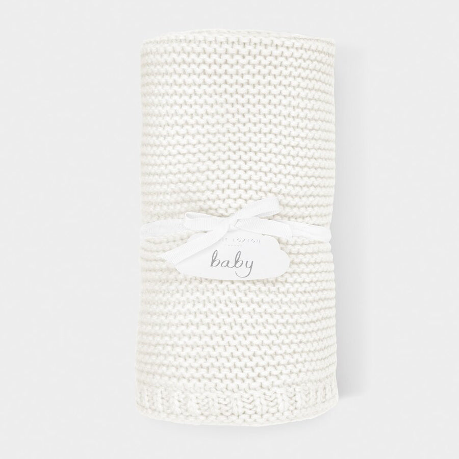 Close-up of white cotton knitted baby blanket showing the soft woven knit and gentle cotton finish.