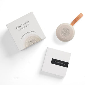 Drift Away packaging and instruction booklet arranged next to the round taupe sound machine.