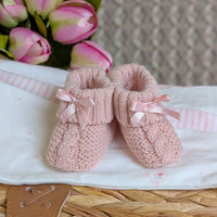 Pair of pink knitted baby booties with ribbons.