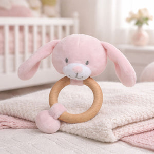 A pink baby hand rattle bunny rabbit theme on a wooden teething ring.