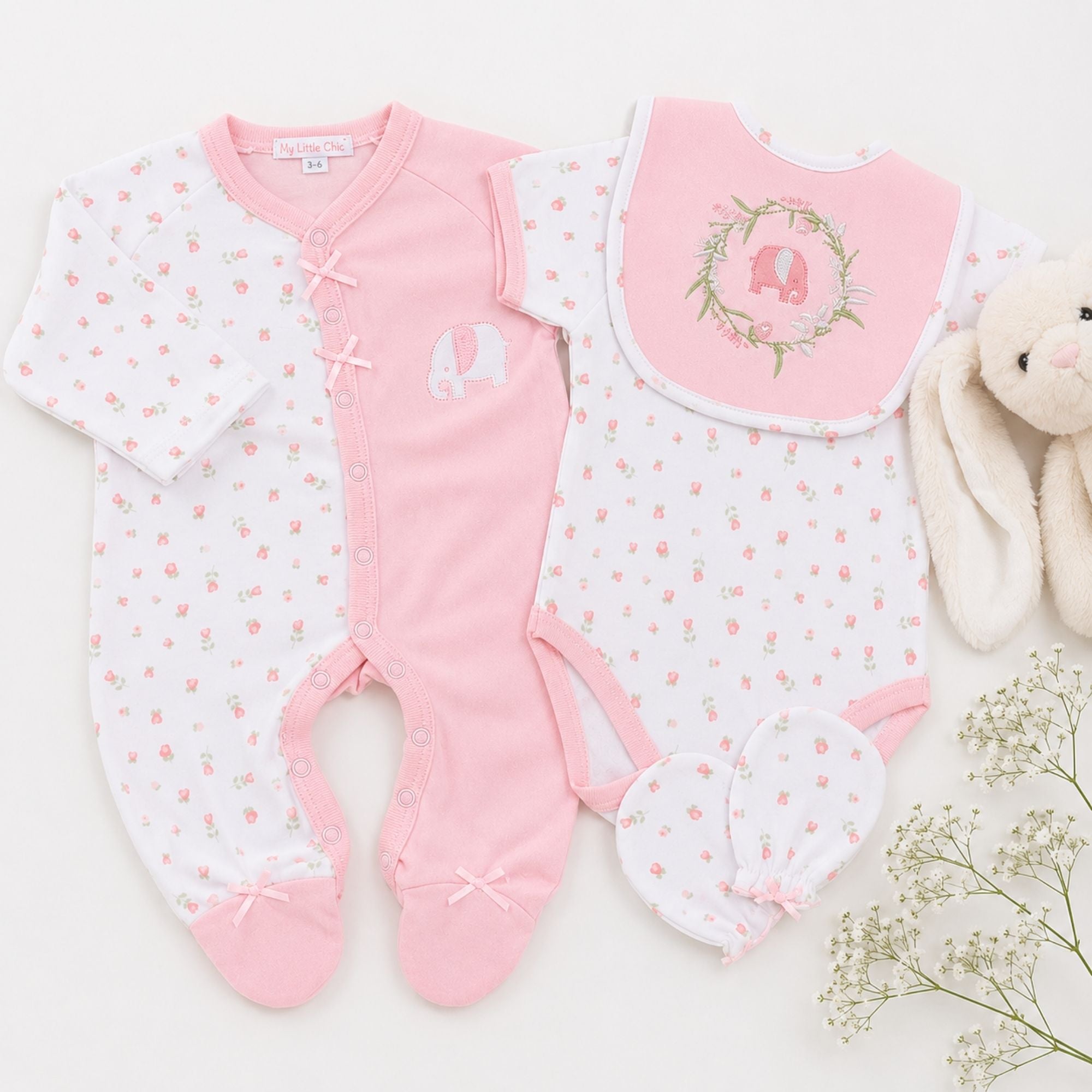 Set of pink baby clothes including romper, vest and baby bib.