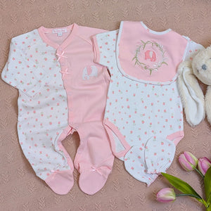 Set of pink baby clothes including romper, vest and baby bib.