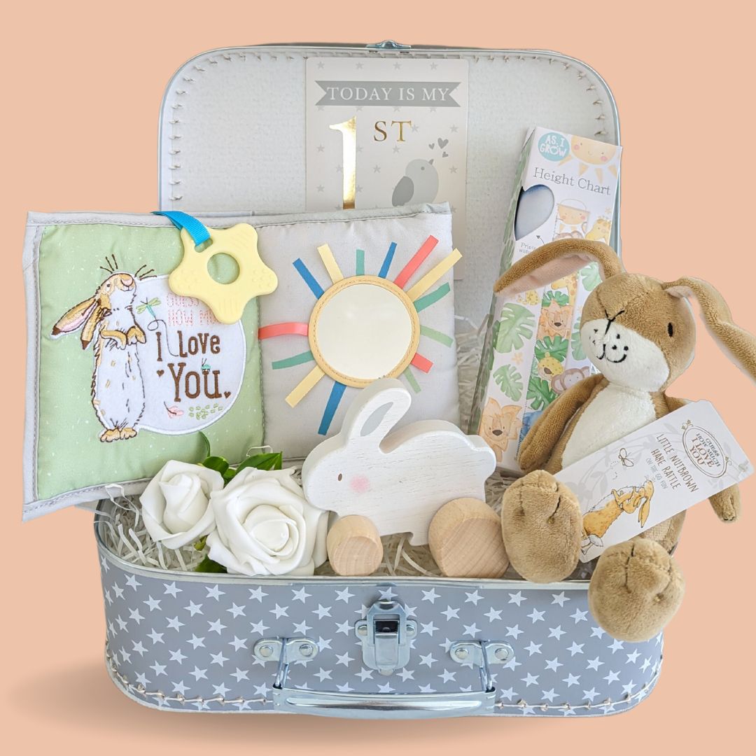 Baby&#39;s first birthday gift hamper with soft book, height chart, bunny soft toy and wooden sensory toy.