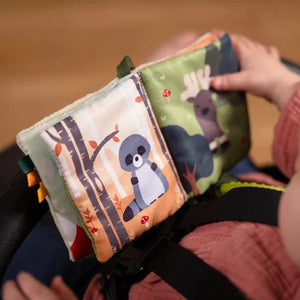 Open forest soft baby book showing woodland animal pages while a child holds it