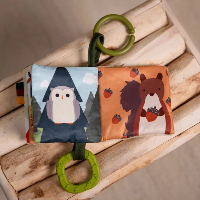 Open forest soft baby book showing owl and squirrel illustrations with green rings
